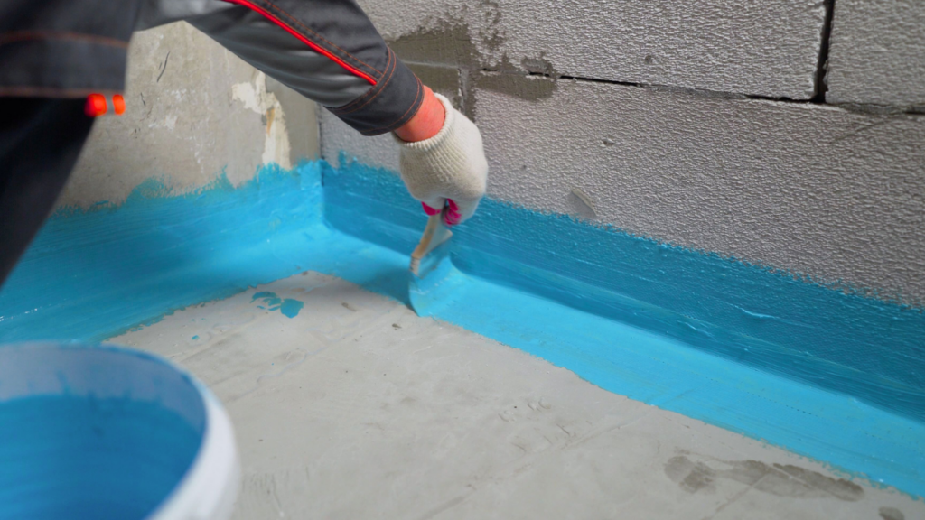 a person brushing the space between floor and wall with blue sealant.